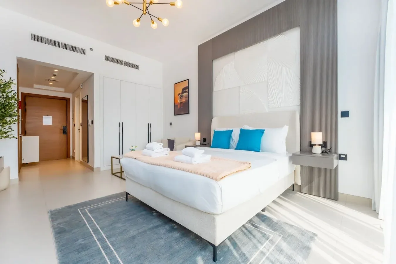 Un dormitorio luminoso cuenta con una cama grande y cojines azules.