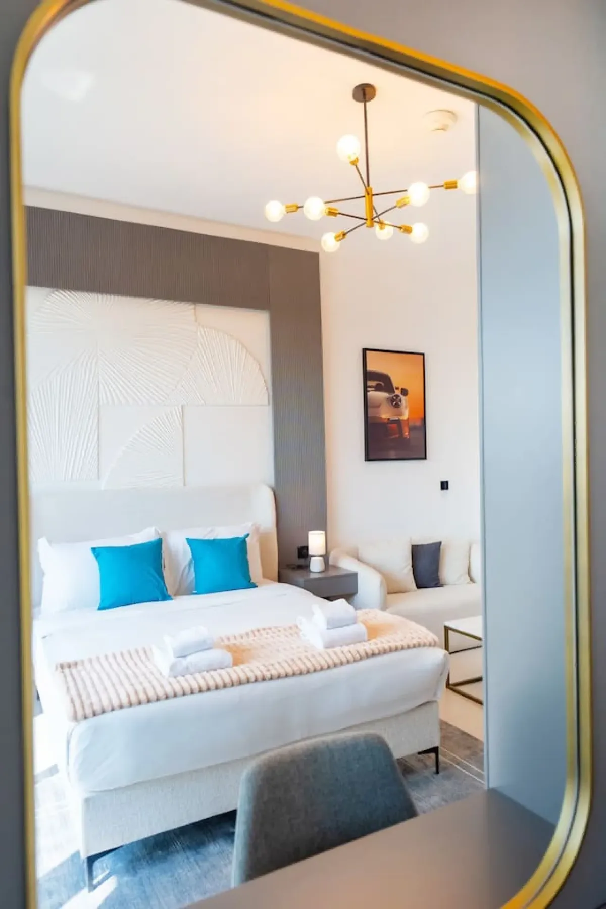 Un dormitorio luminoso con una cama tendida y una lámpara colgante.