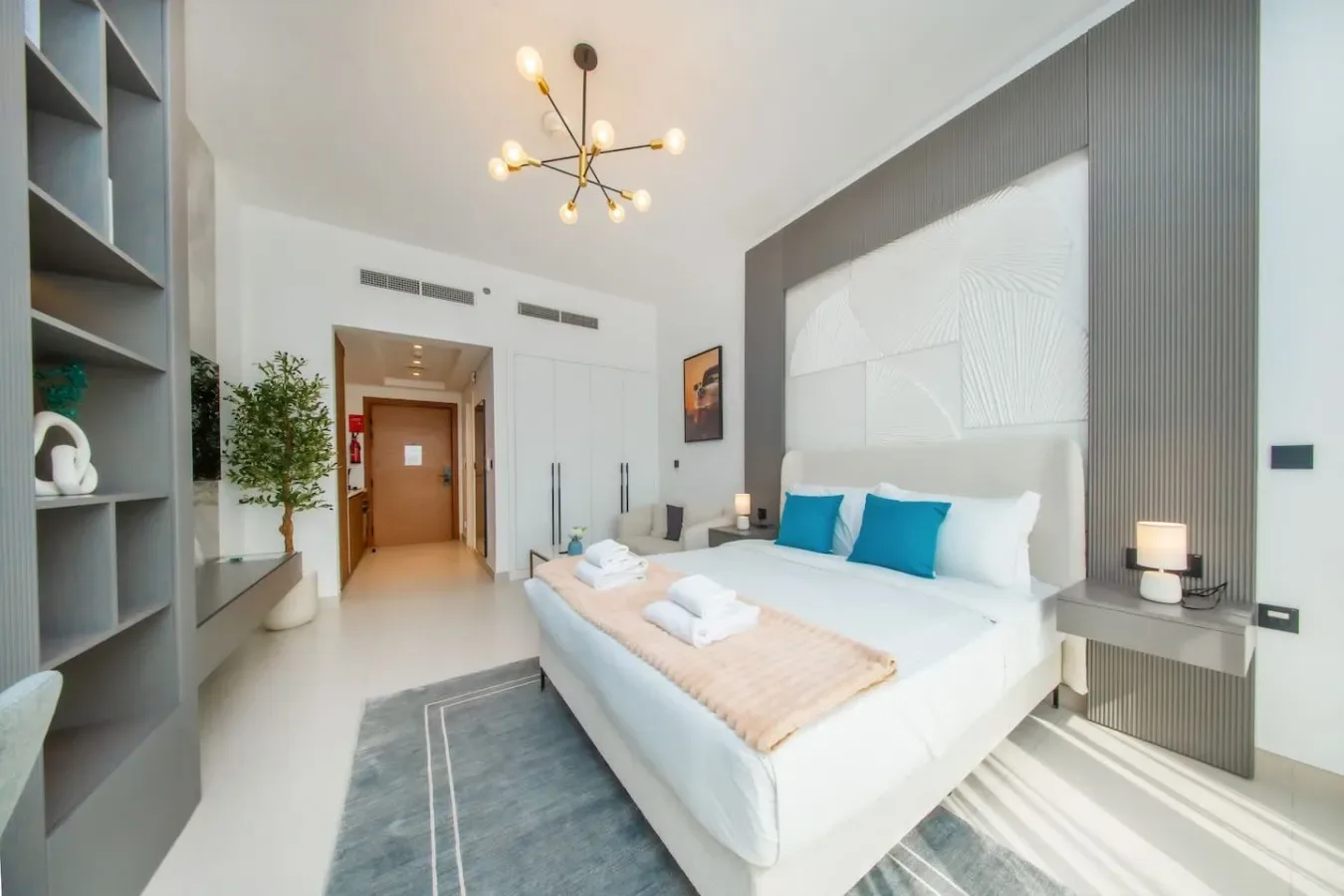 Un dormitorio luminoso con una cama bien hecha y una pequeña zona de estar.