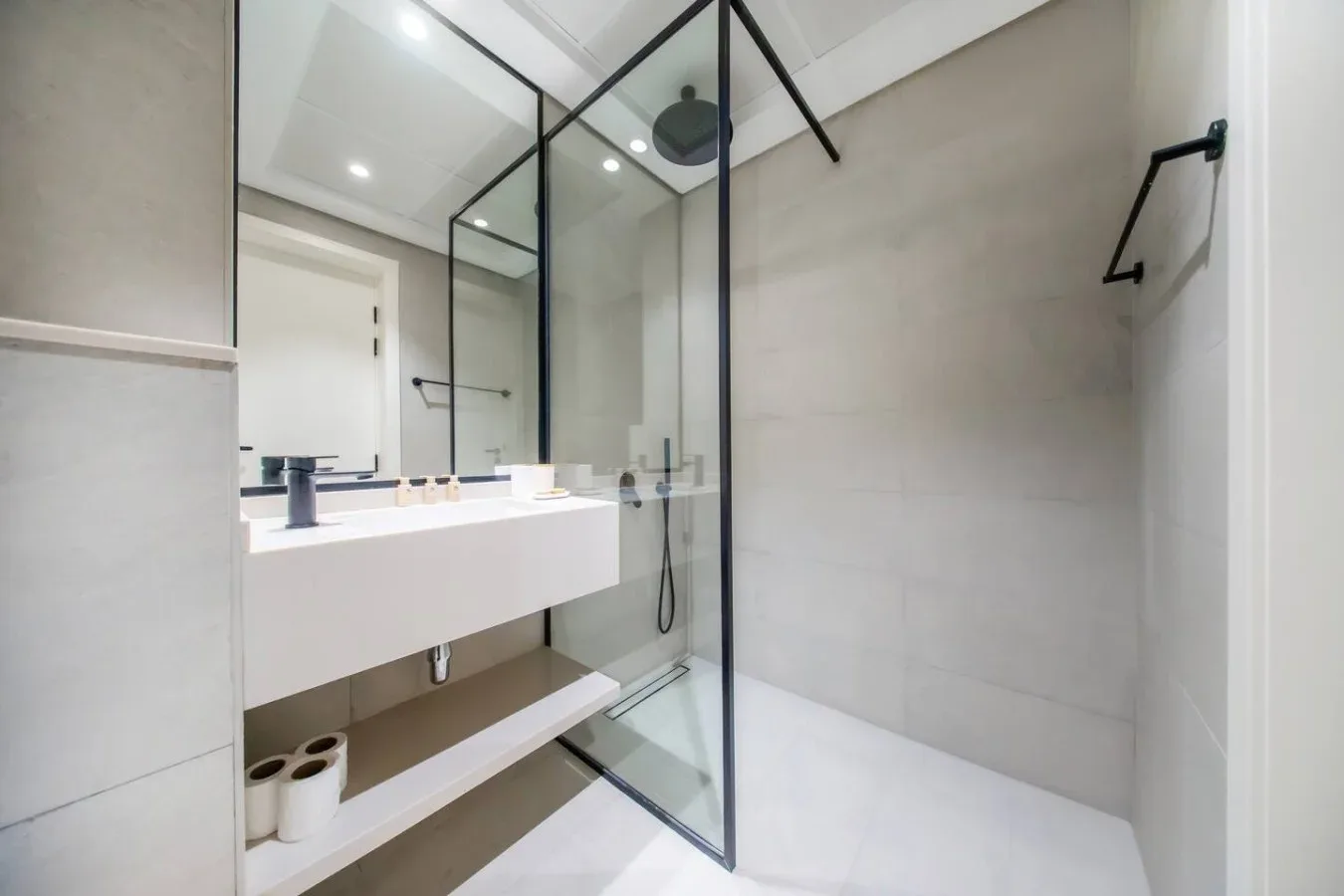 Un baño luminoso con un lavabo largo y una ducha de vidrio.