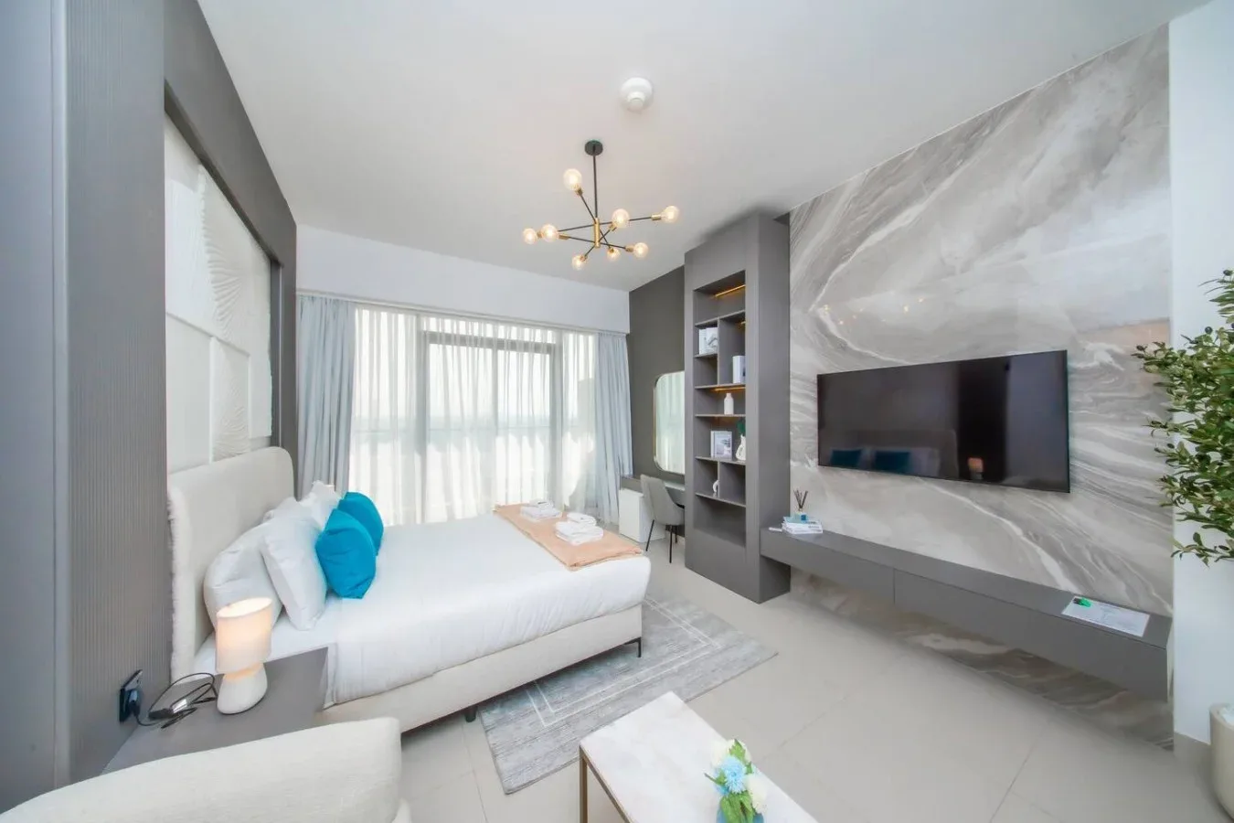 Una zona de descanso luminosa con una cama junto a un televisor montado en la pared.