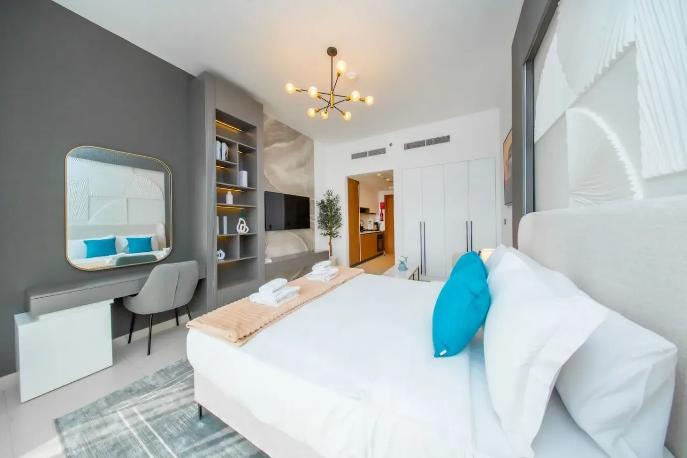 Un dormitorio luminoso con una cama amplia, un escritorio y estanterías empotradas.
