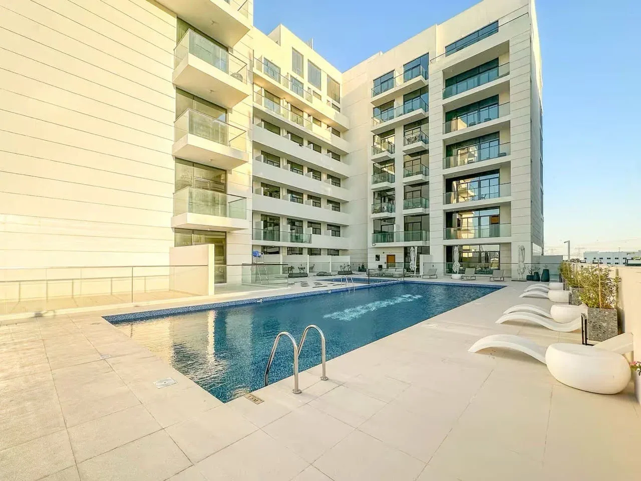Una piscina al aire libre está junto a un edificio moderno de varias plantas.