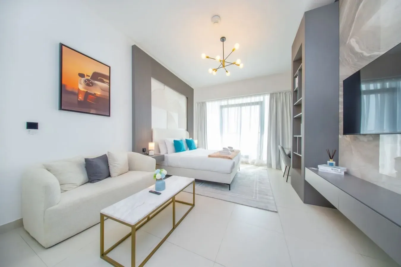 Una sala luminosa con zona de estar, mesa de centro y cama junto a la ventana.