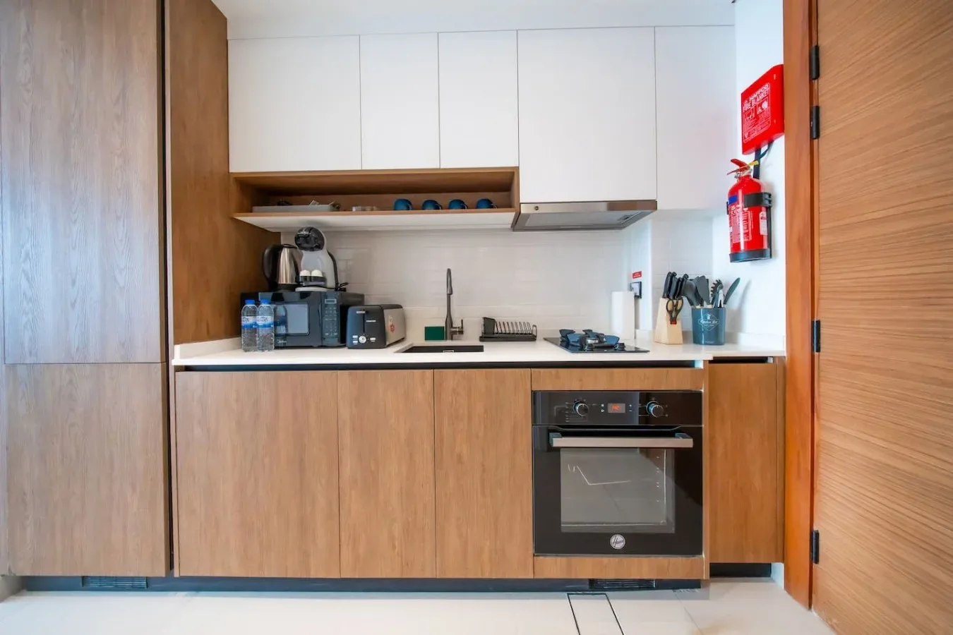 Una cocina compacta con gabinetes de madera, una encimera y un horno.