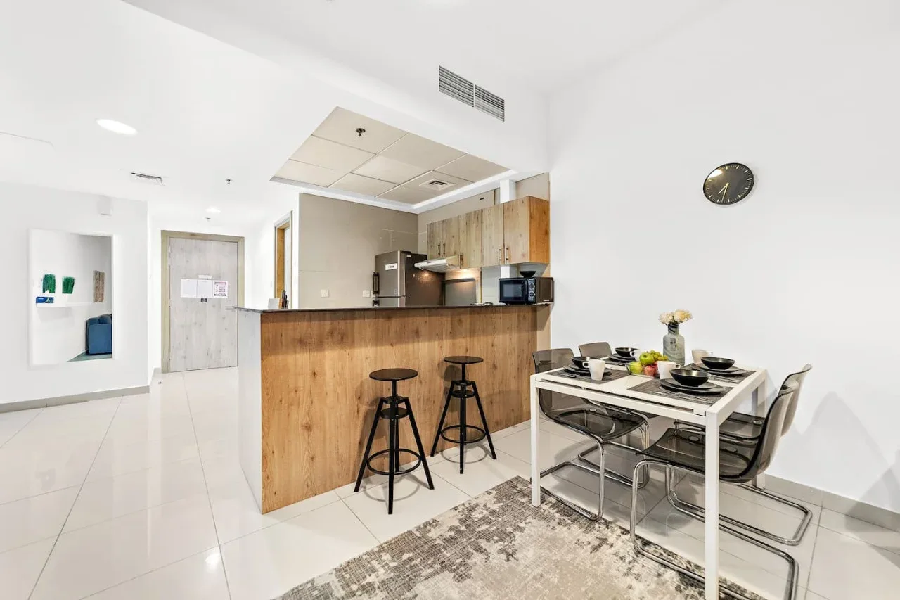 Una cocina abierta con comedor, barra de madera y mesa.