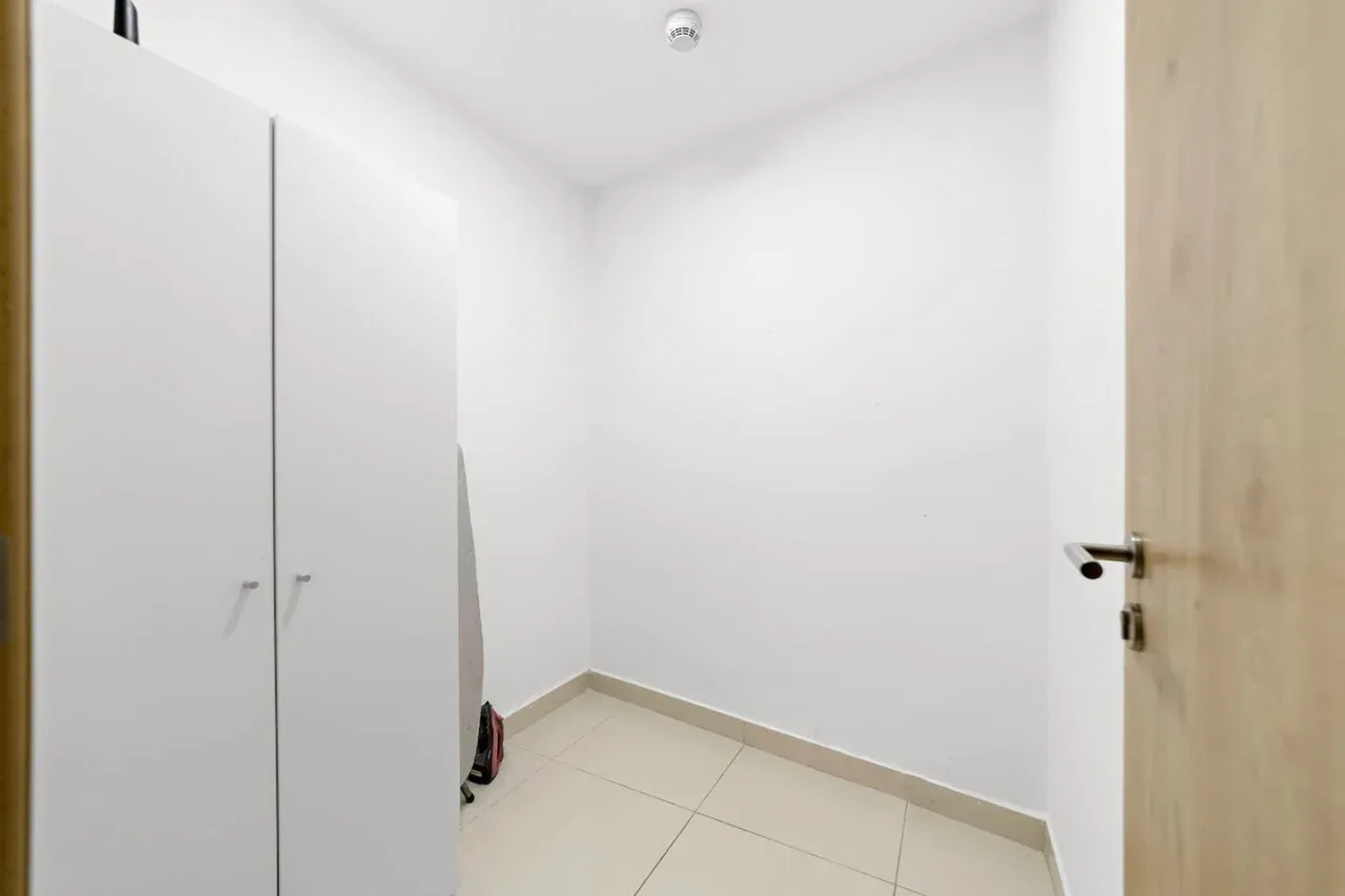 Una pequeña habitación blanca con un armario empotrado y una puerta abierta.