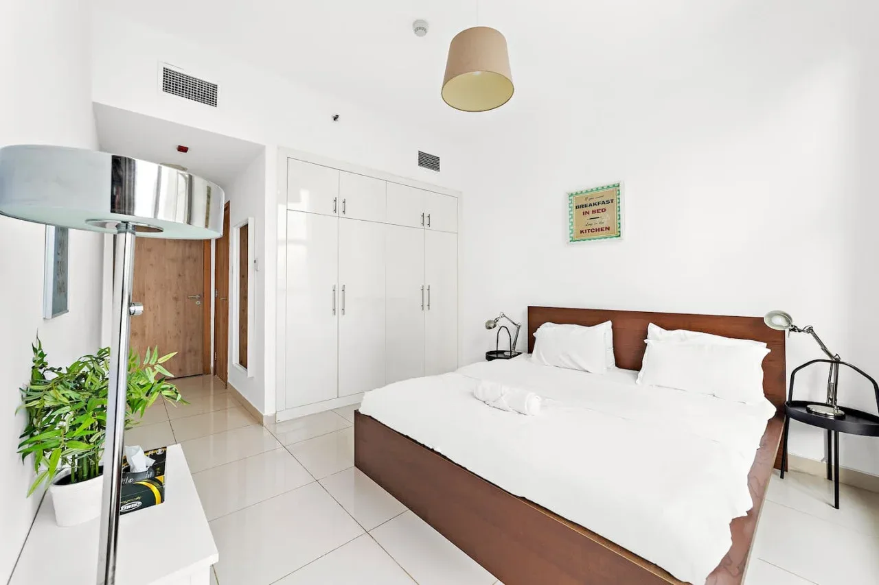 Un dormitorio luminoso con una cama blanca y armarios empotrados.