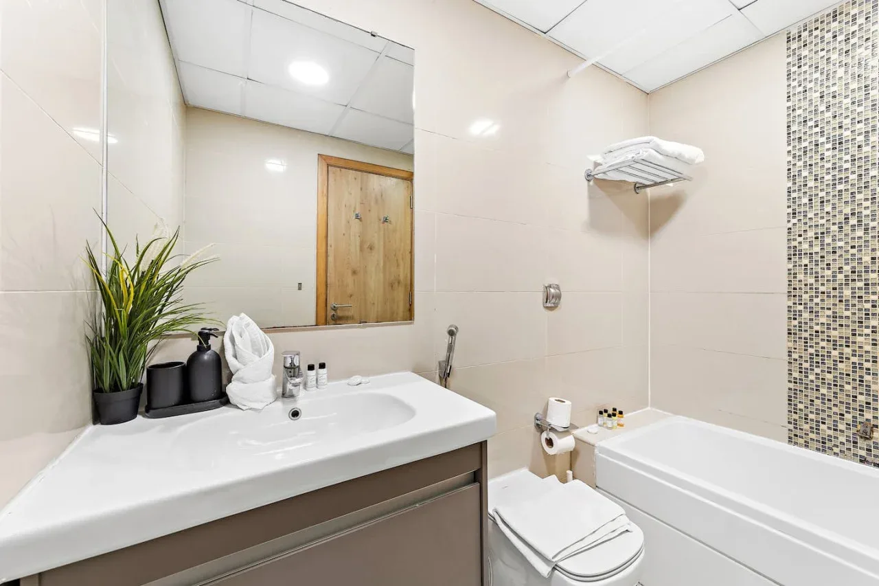 Un baño luminoso con lavabo, inodoro y bañera.
