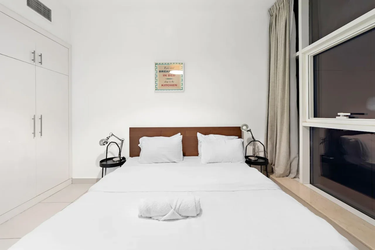 Un dormitorio luminoso con una cama bien hecha y mesillas de noche.