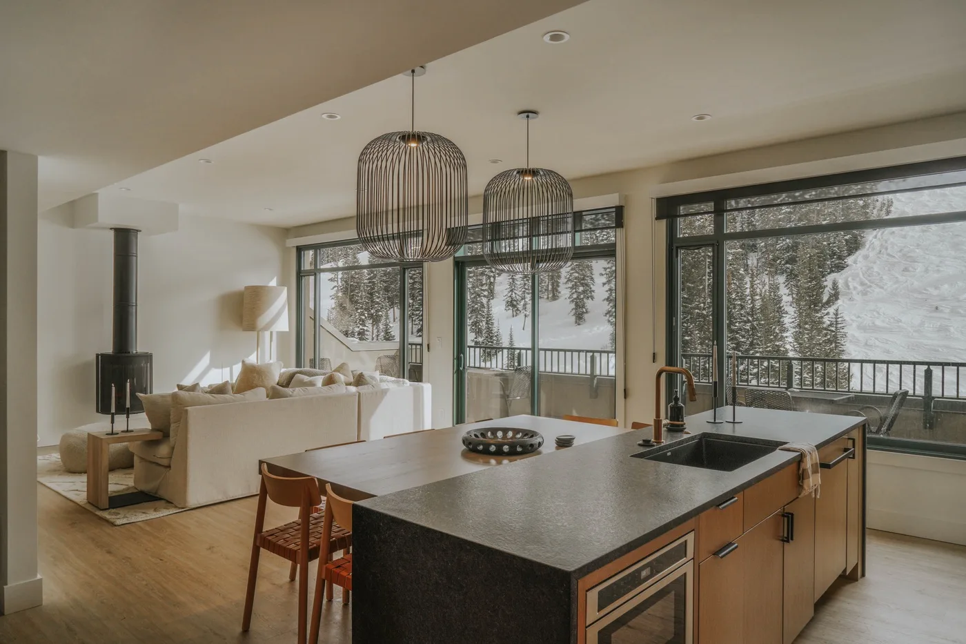 An open-plan kitchen and living area with a large island and windows overlooking trees.