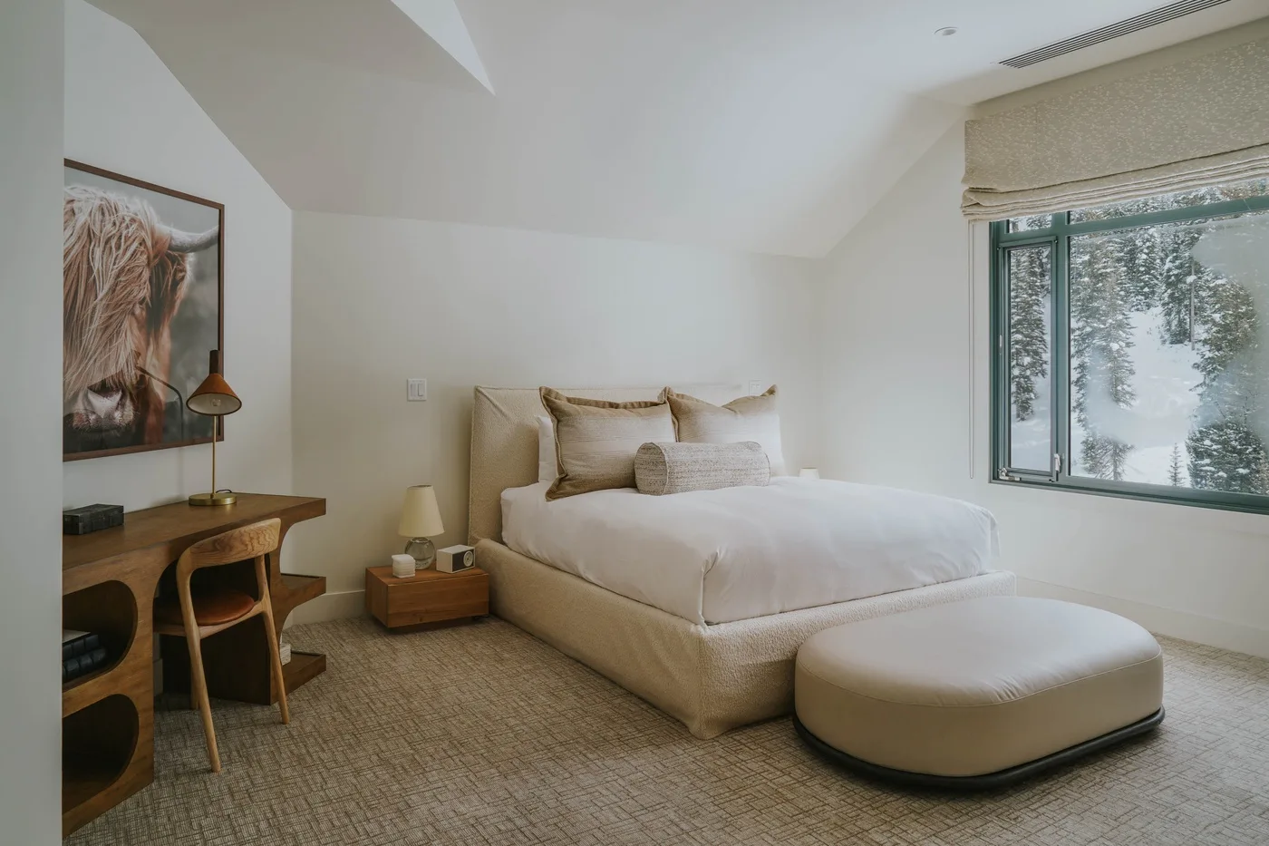 A bright bedroom with a neatly made bed beside a large window.