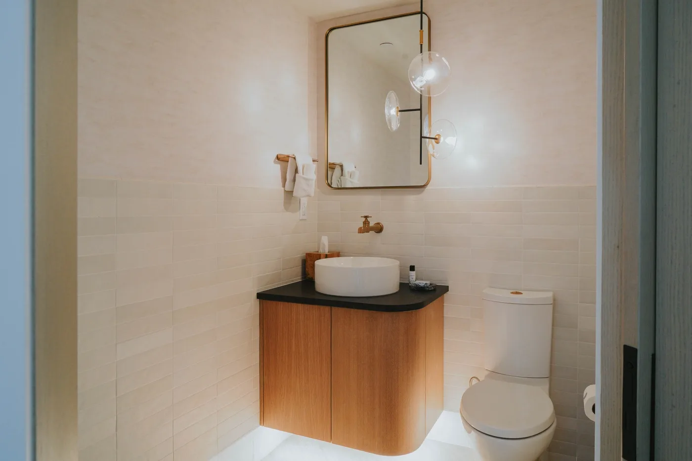 A bathroom with a vanity, vessel sink, mirror, and toilet.