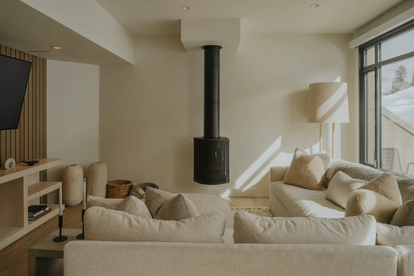 A bright living room with light-colored seating and a central black fireplace.