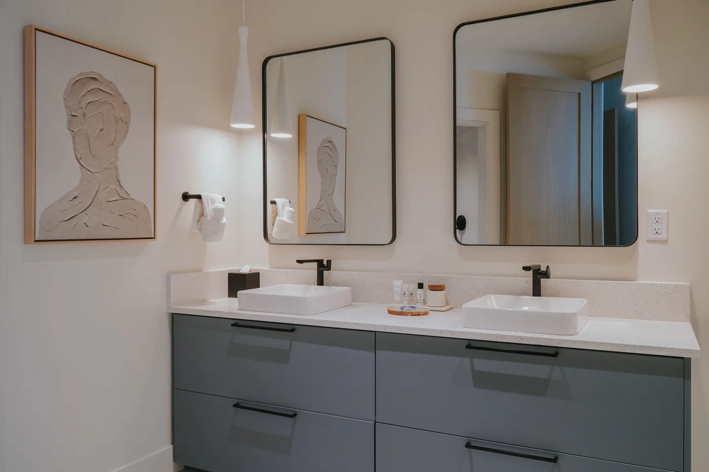 A bathroom vanity with two sinks, mirrors, and framed artwork.