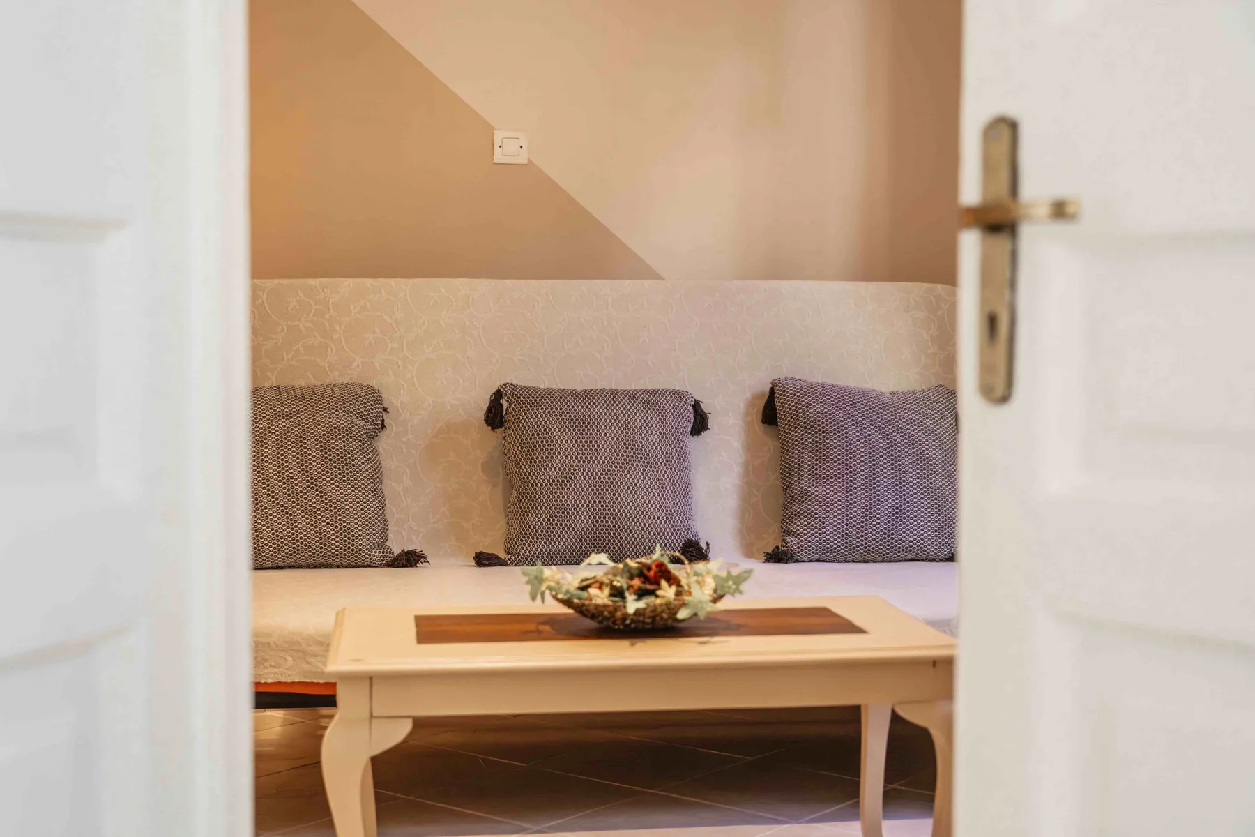Una zona de estar con una mesa baja y cojines junto a la pared.