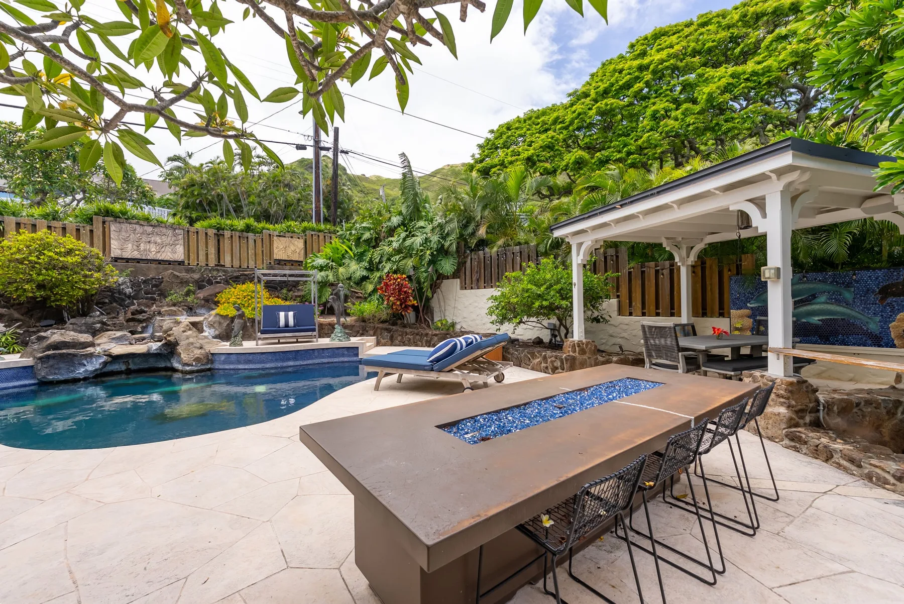 Un patio con piscina, mesa de comedor y una zona de estar cubierta.
