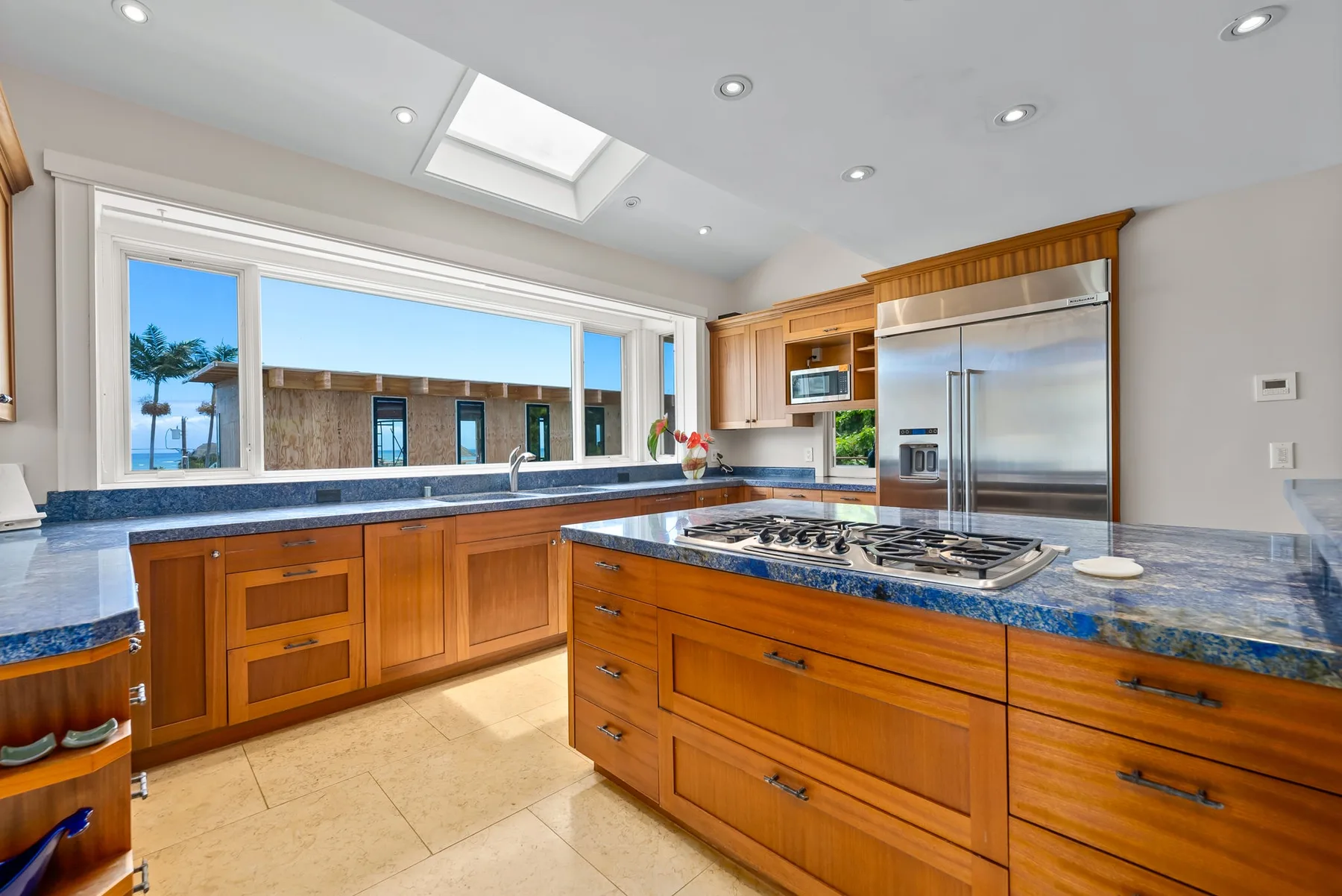 Una cocina luminosa con gabinetes de madera, encimeras azules y una gran isla central.