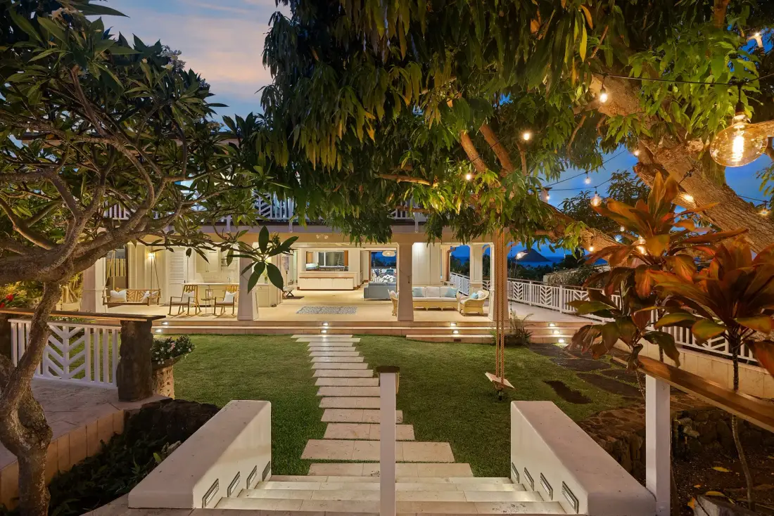 Un patio ajardinado con piedras de paso conduce hacia un edificio iluminado.