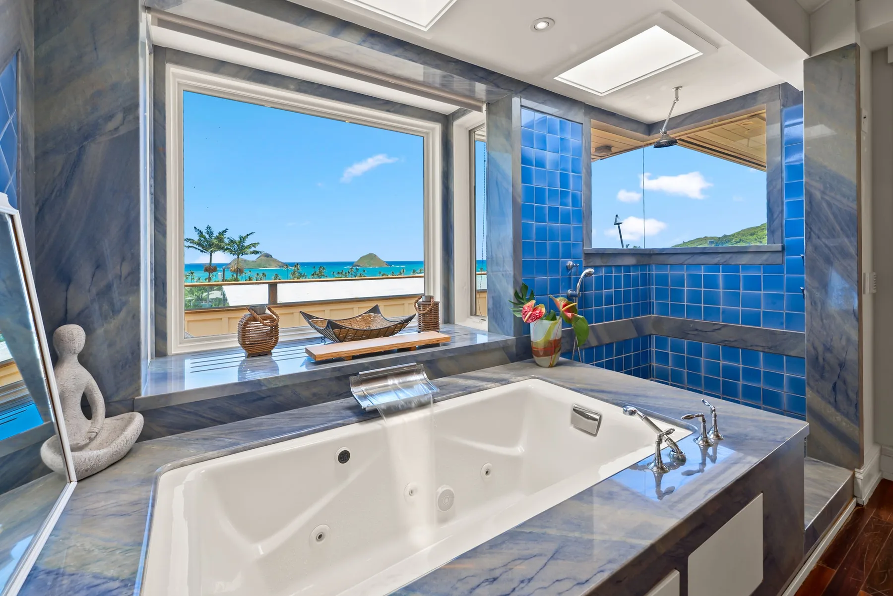 Una bañera grande está junto a ventanas con vistas a la costa.