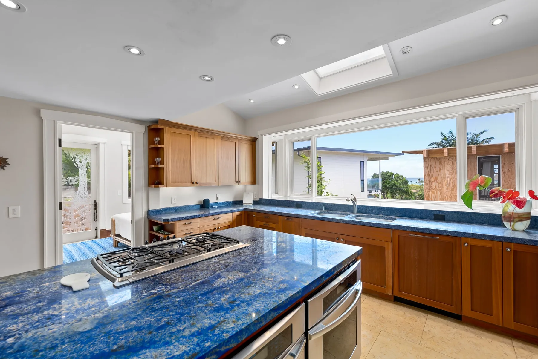 Una cocina luminosa con encimeras azules, gabinetes de madera y ventanas grandes.