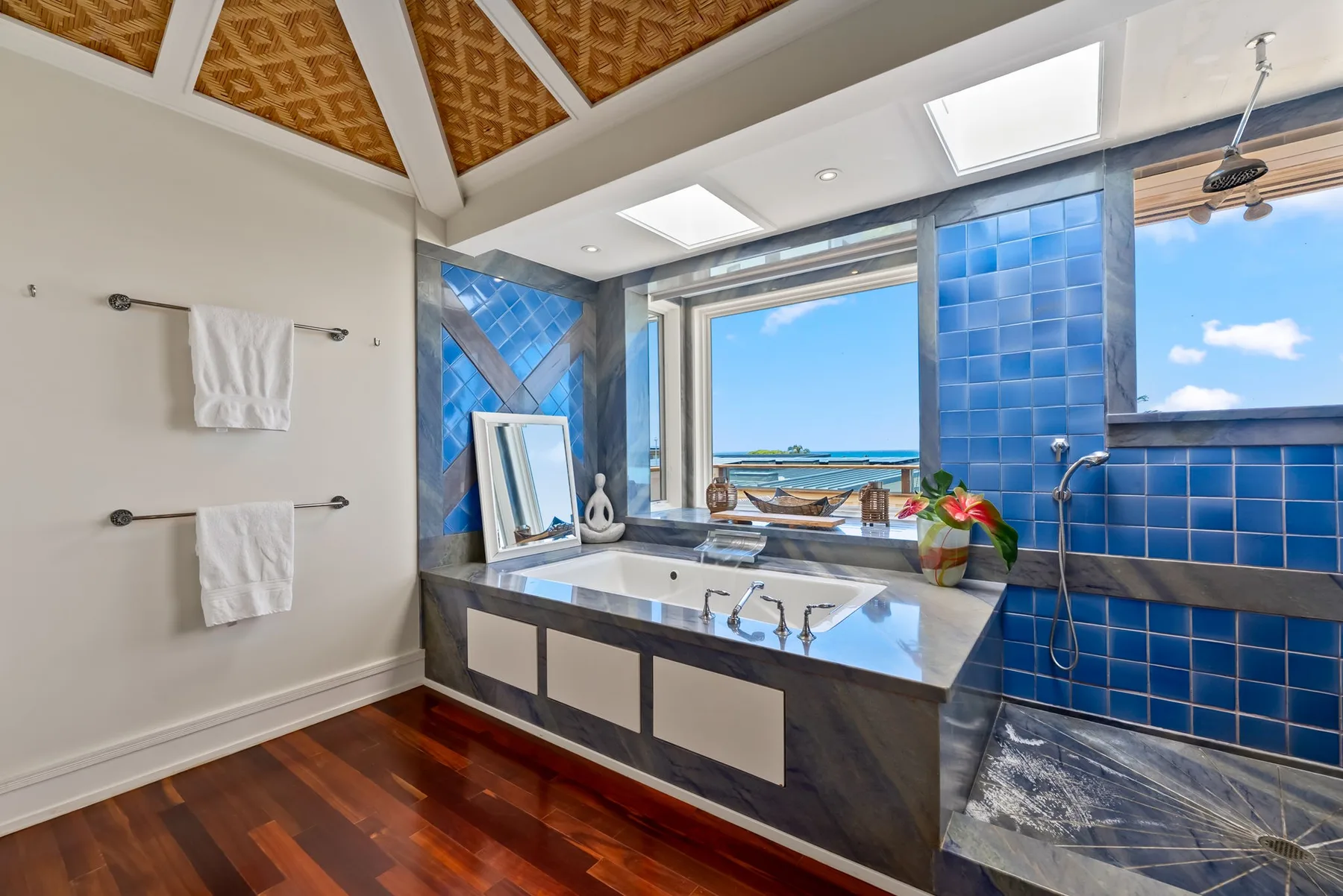 Un baño luminoso con un amplio tocador y azulejos azules junto a una vista abierta.