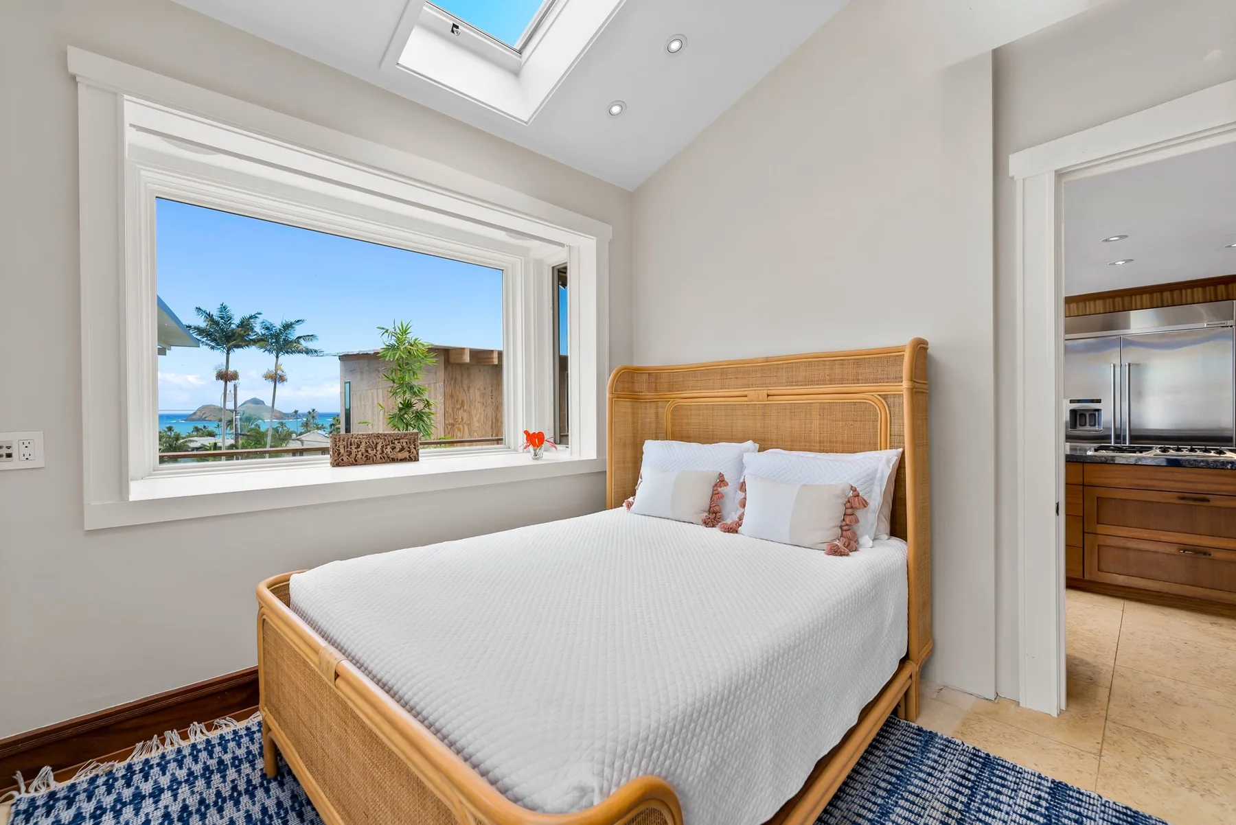 Un dormitorio luminoso con una cama bajo una claraboya y una ventana amplia.