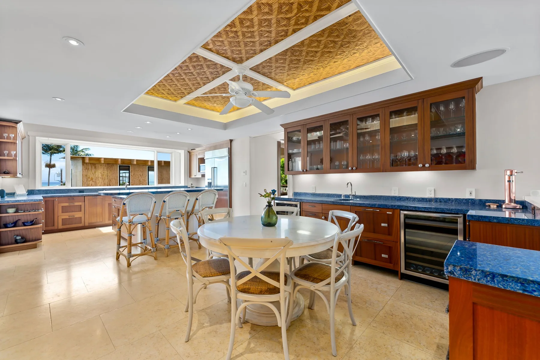 Una amplia cocina-comedor con gabinetes de madera, una mesa central y un techo decorado.