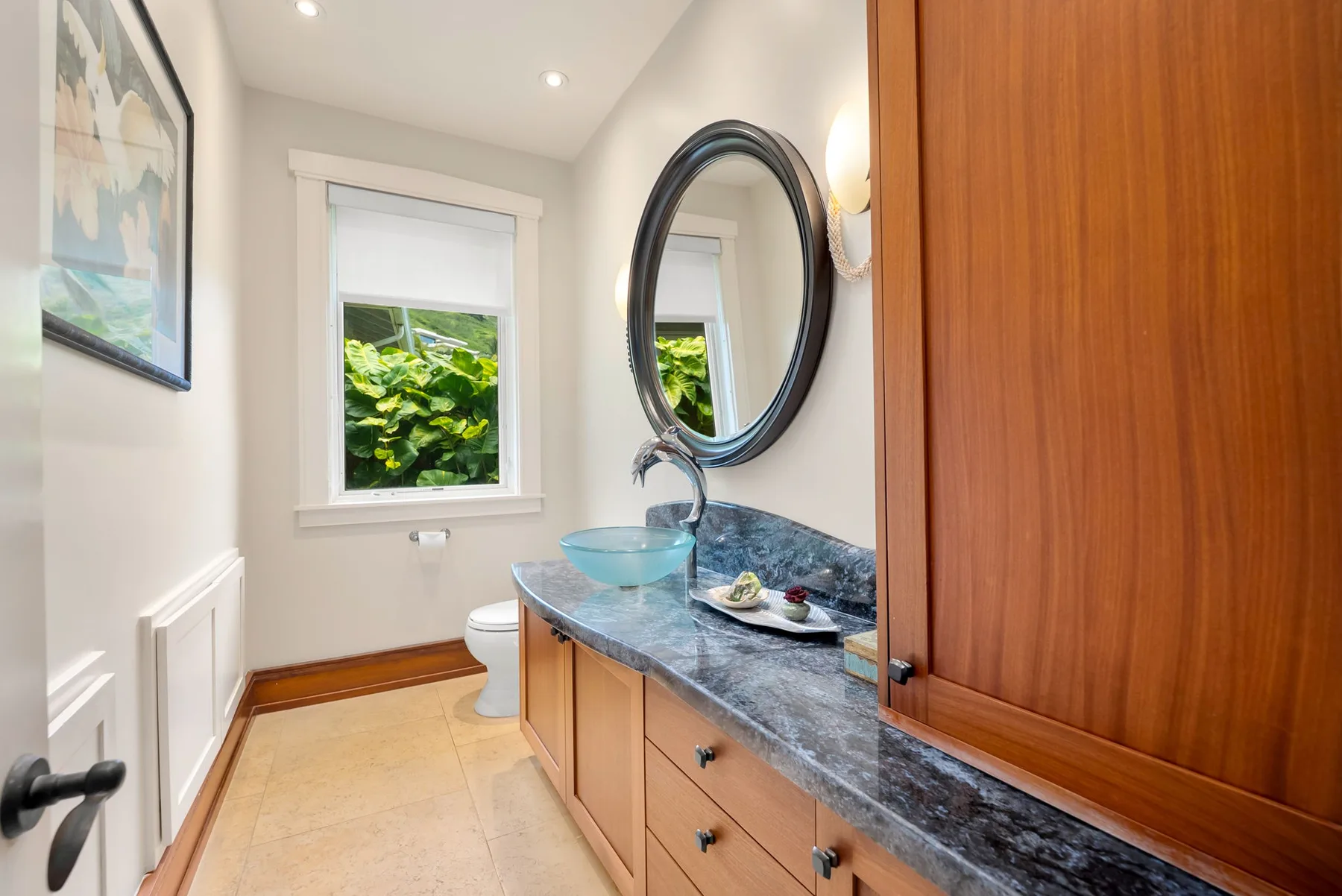 Un baño con lavabo, tocador y una ventana con vistas a la vegetación.