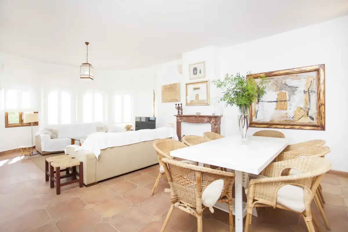 A bright living and dining room with wicker seating around a table.