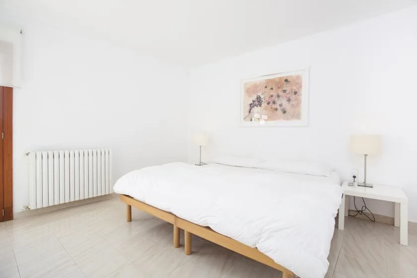 A bright bedroom with a bed, bedside tables, and a radiator.