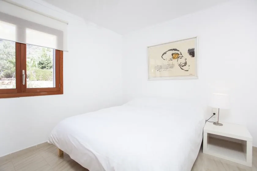 A bright bedroom with a bed beneath framed wall art.