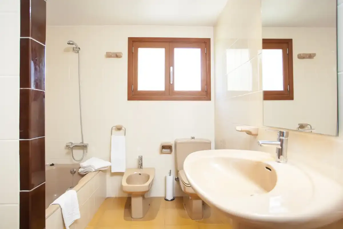 A bathroom with a bathtub, sink, toilet, and window.