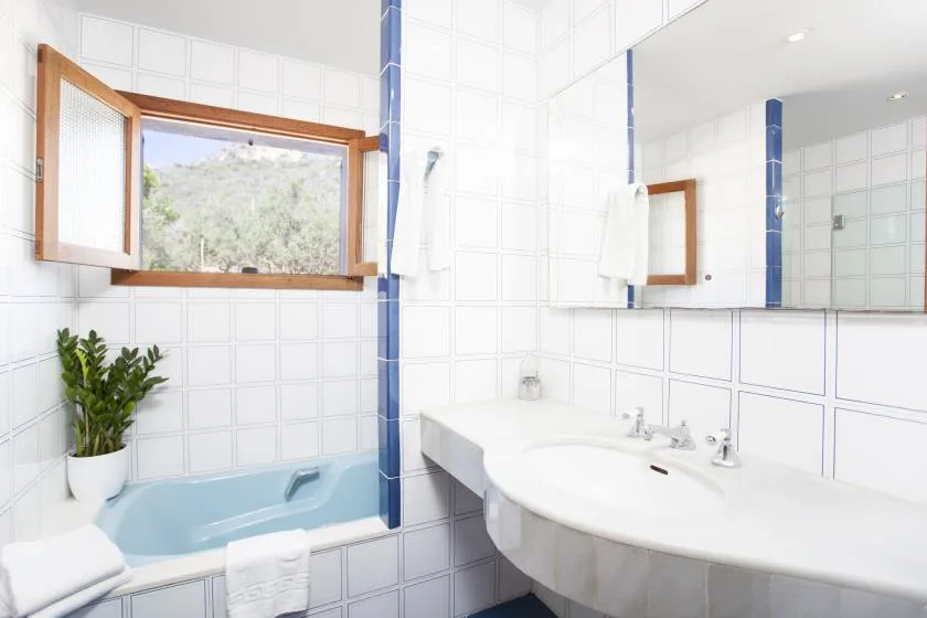A tiled bathroom with a bathtub, sink, and window.