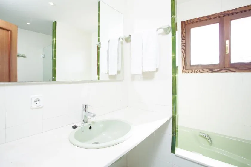 A bright bathroom with a sink, mirror, and bathtub.