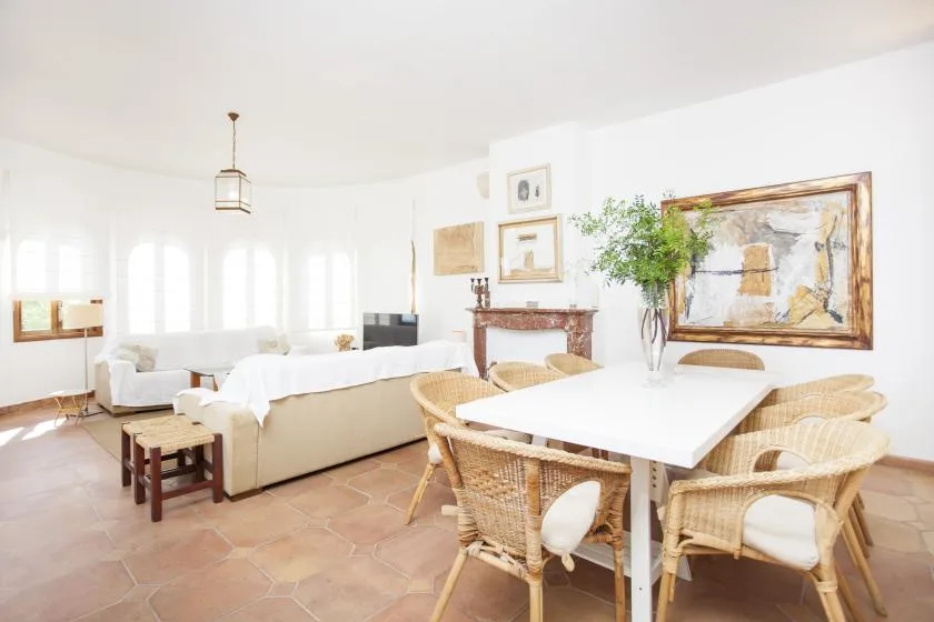 A bright living and dining room with seating around a white table.