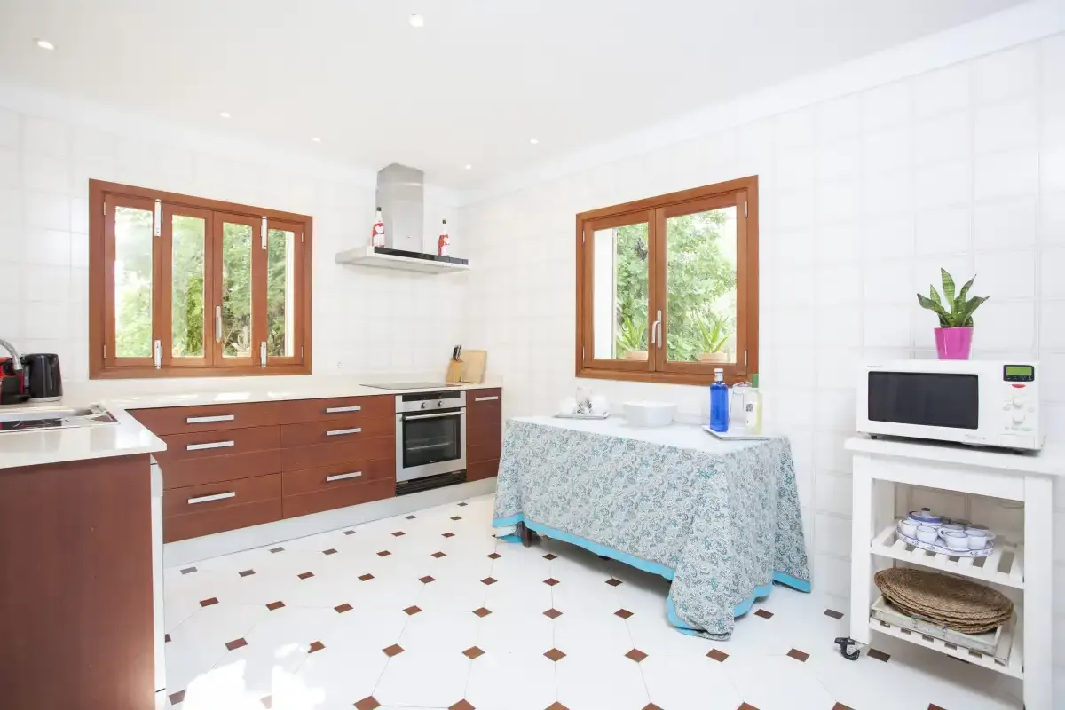 A bright tiled kitchen with wooden cabinets and a covered table.