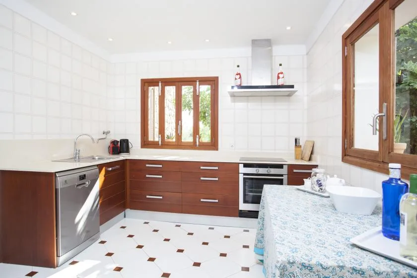 A bright kitchen with wooden cabinets, a sink, and a dining table.