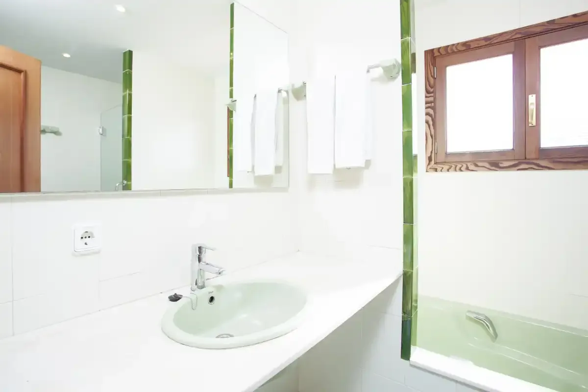 A bright bathroom with a sink, mirror, and bathtub.