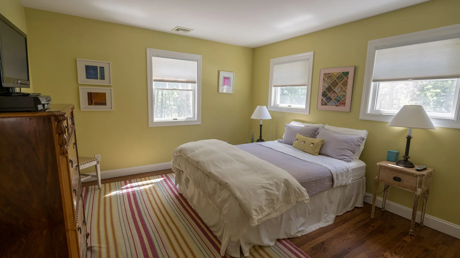 Un dormitorio con una cama, una alfombra a rayas y ventanas.