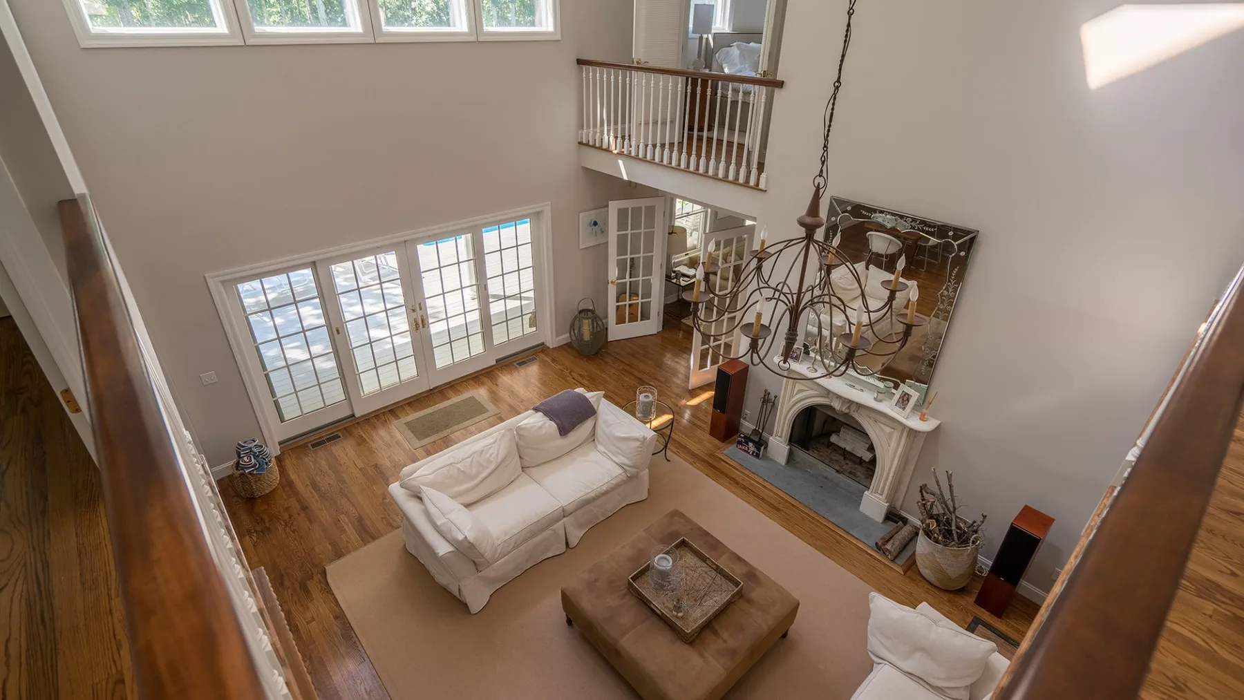 A bright living room with a seating area, tall windows, and a fireplace.
