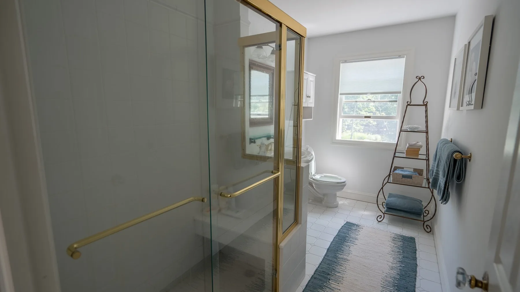 Un baño con ducha de vidrio, inodoro y ventana.