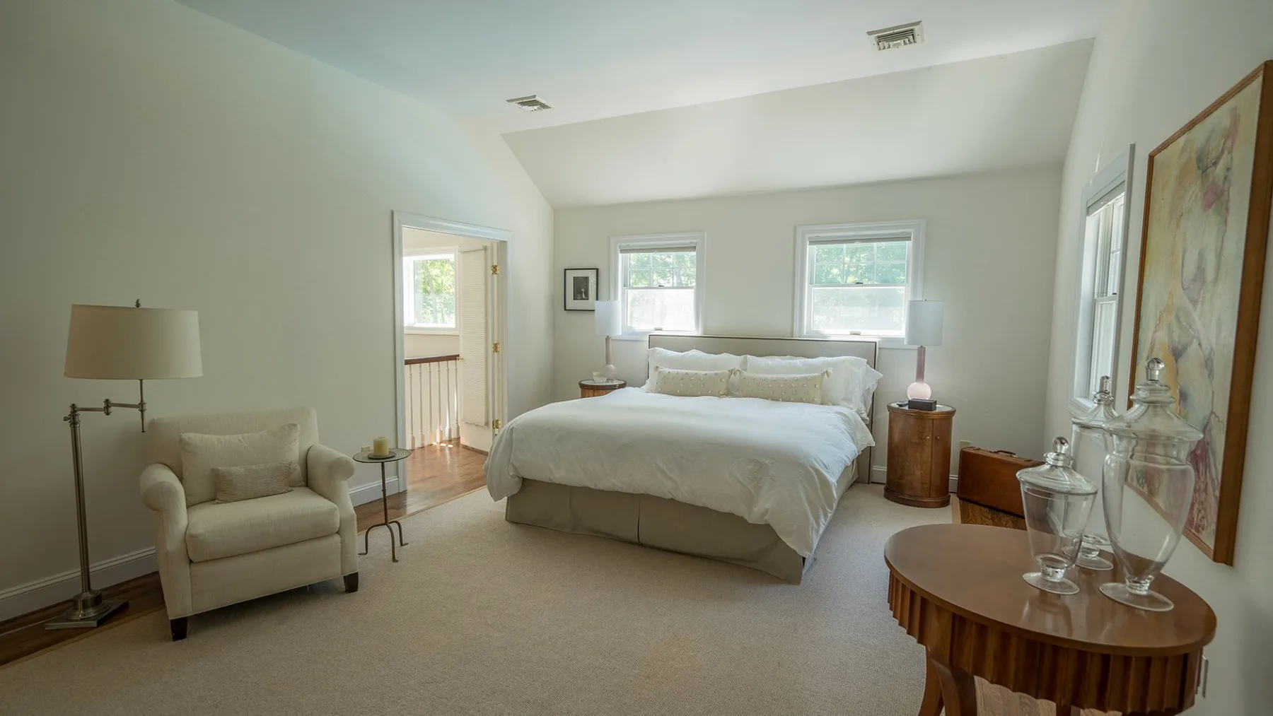 Un dormitorio luminoso con una cama tendida y una zona de estar.