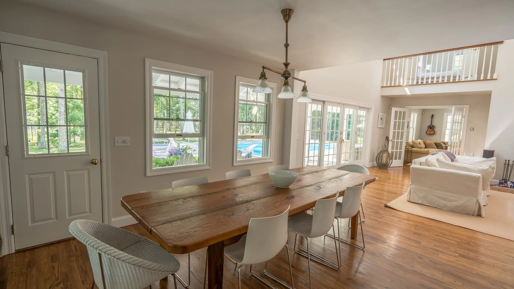 Un comedor luminoso con una mesa larga de madera junto a grandes ventanas.