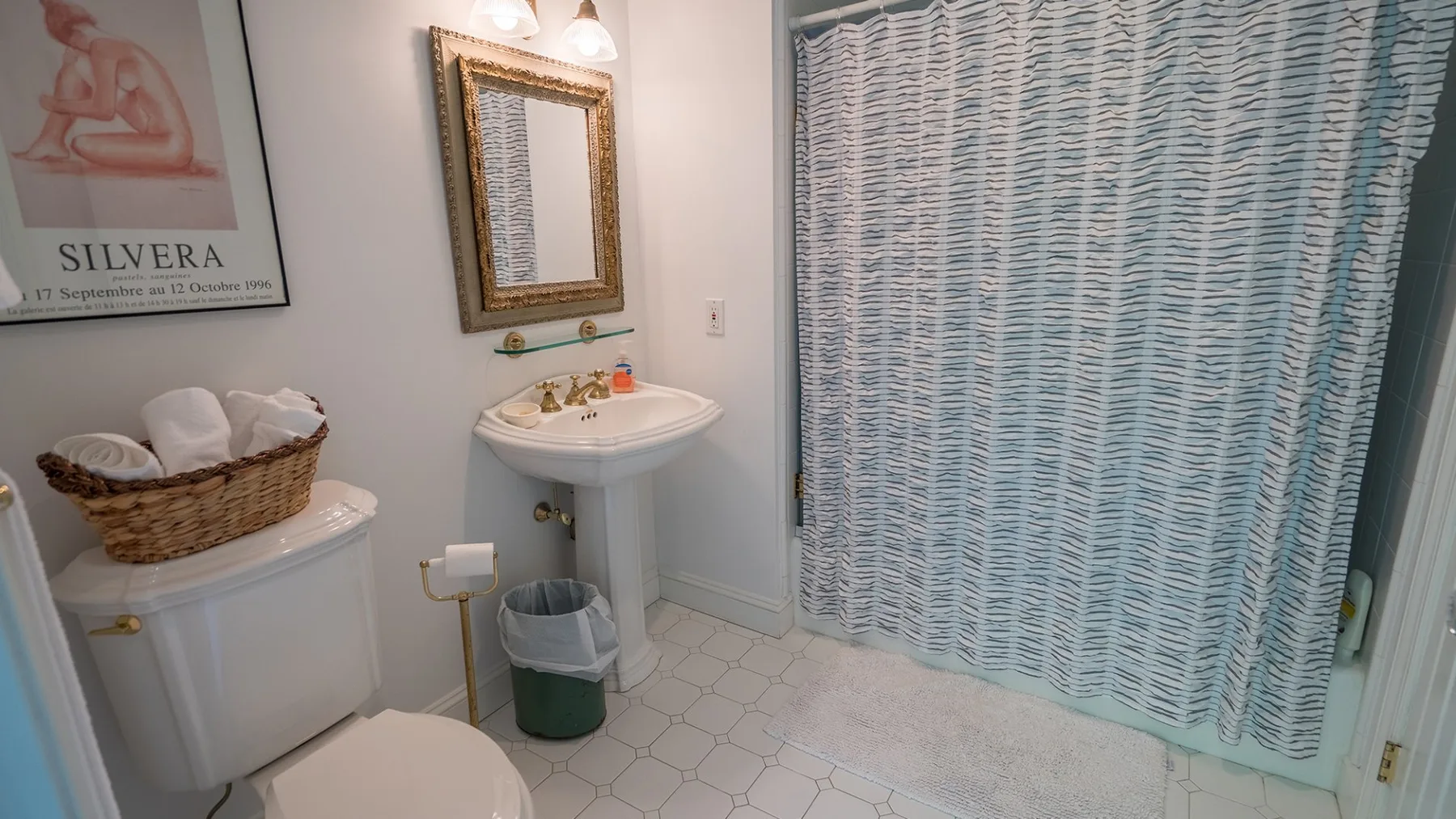 Un baño con lavabo de pedestal, inodoro y cortina de ducha estampada.