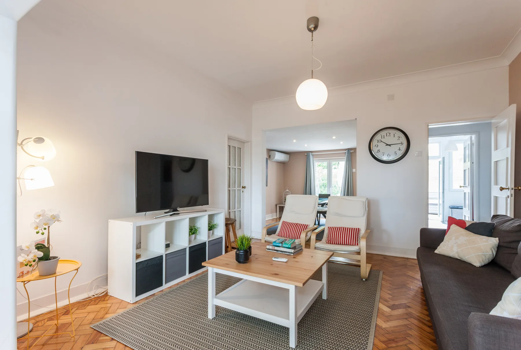 Una sala de estar luminosa con televisor, asientos y una mesa de centro.