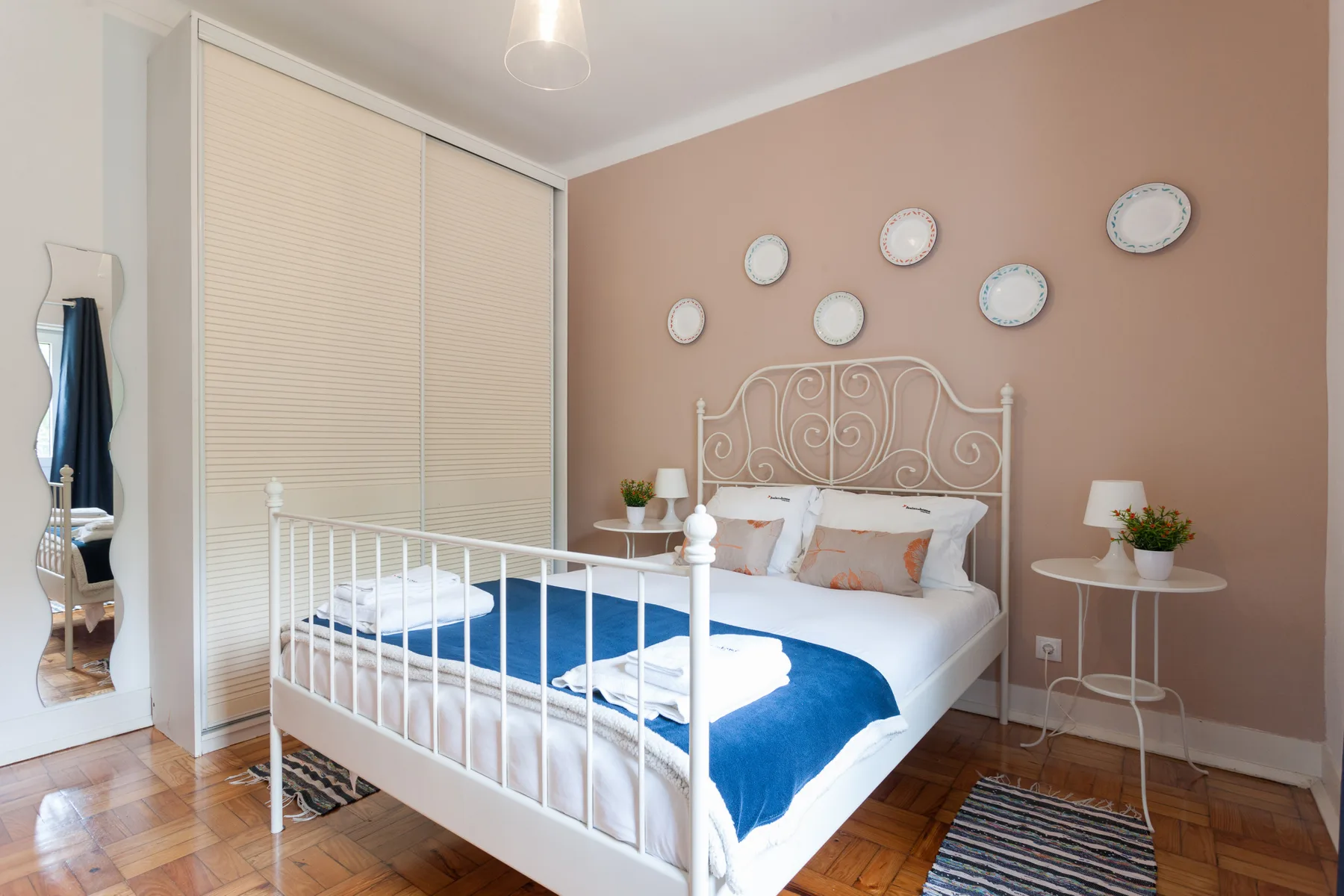 Un dormitorio con una cama blanca, una manta azul y adornos redondos en la pared.