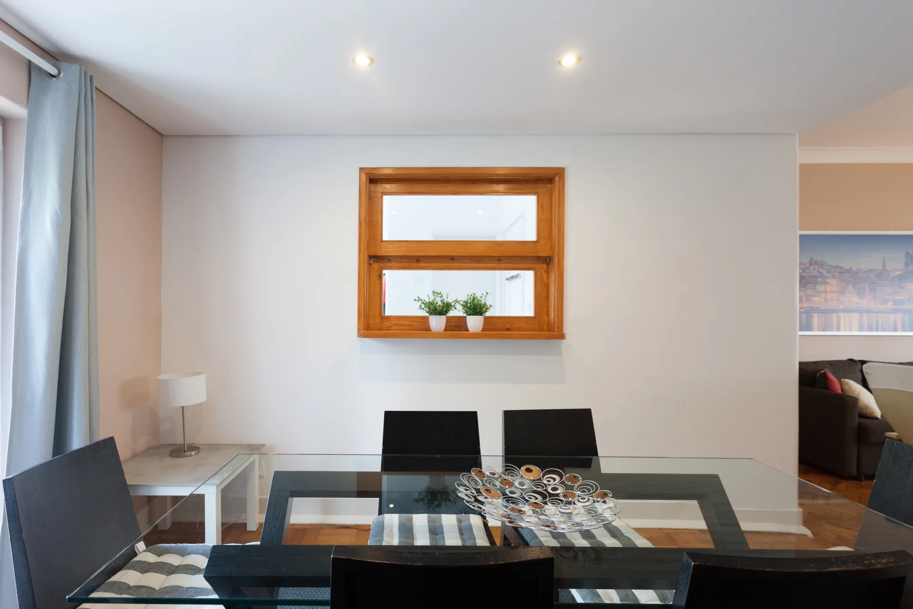 Comedor con una mesa de cristal y una ventana con marco de madera.