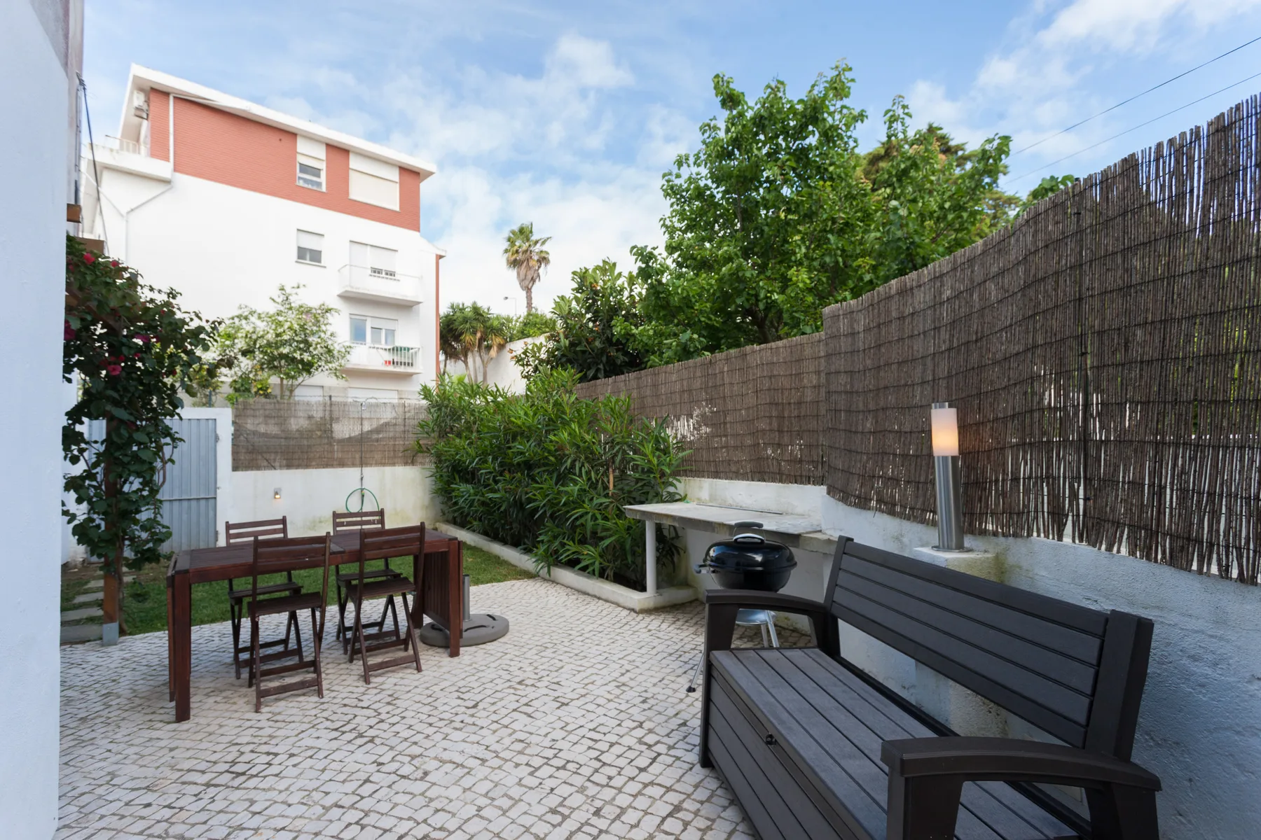 Una terraza exterior pavimentada con asientos, jardineras y un banco.