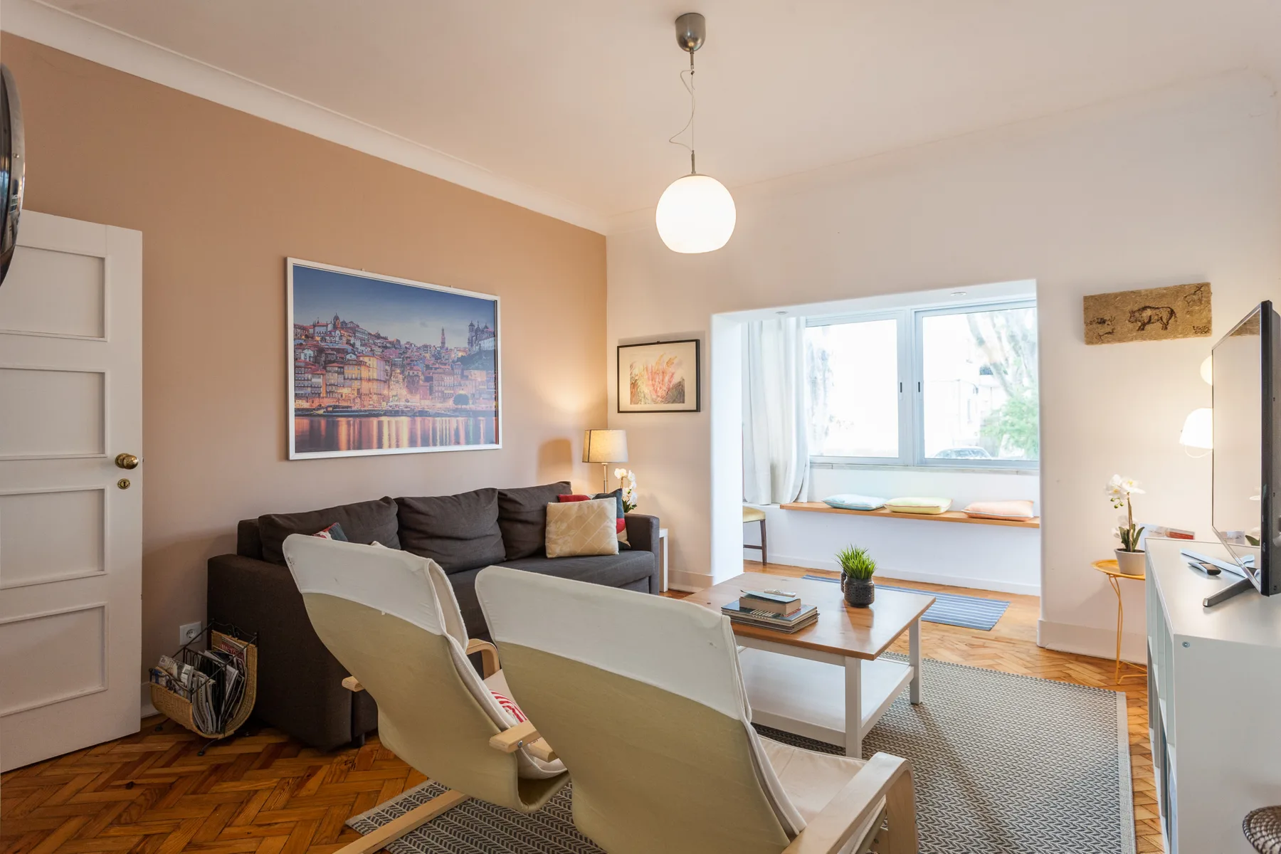 Una sala de estar con asientos alrededor de una mesa de centro junto a una ventana luminosa.